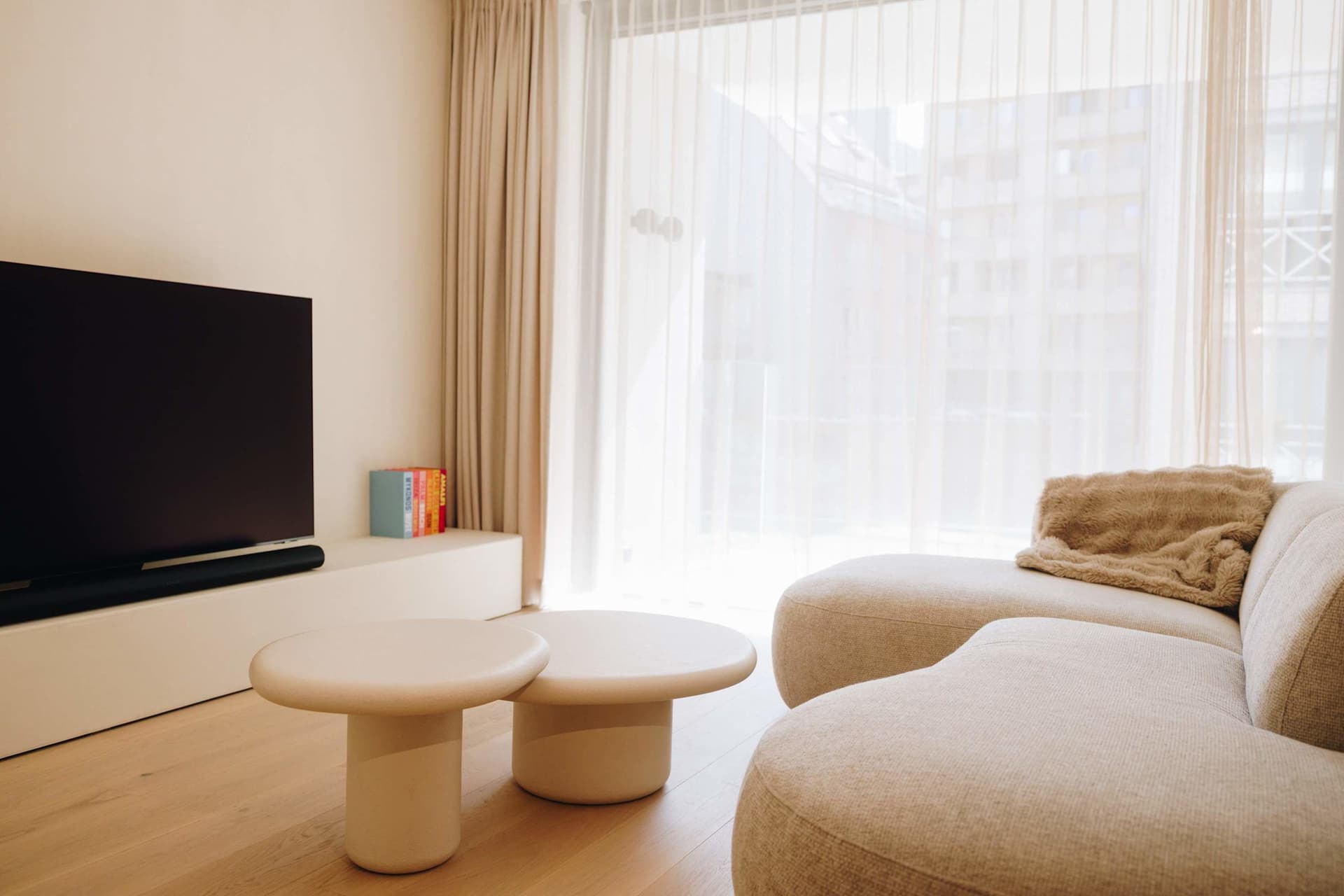 Living room with deep sofa, round coffee table and sheer curtains.