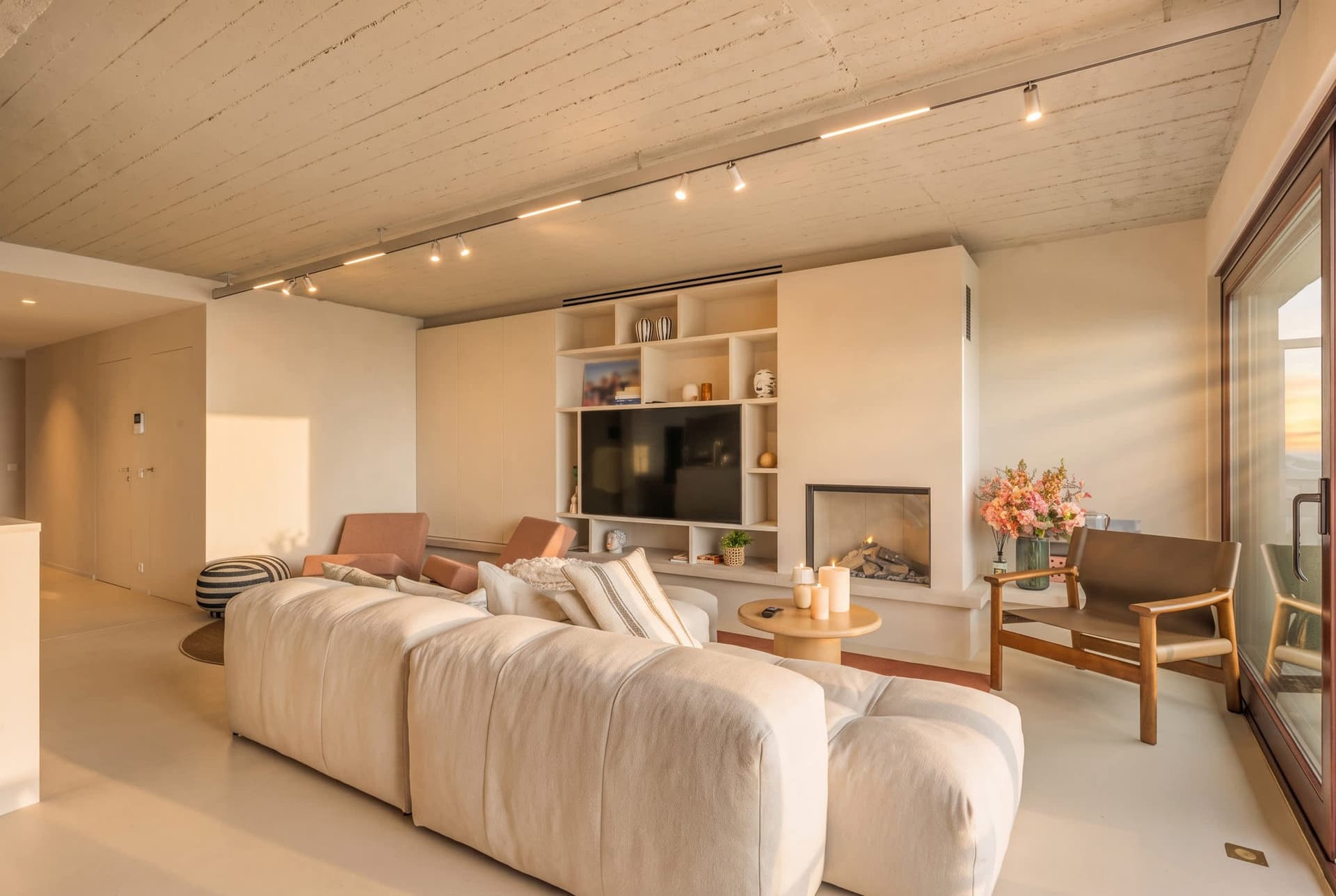 Diepe zetel voor de kastenwand met haard, rechts de balkondeur.