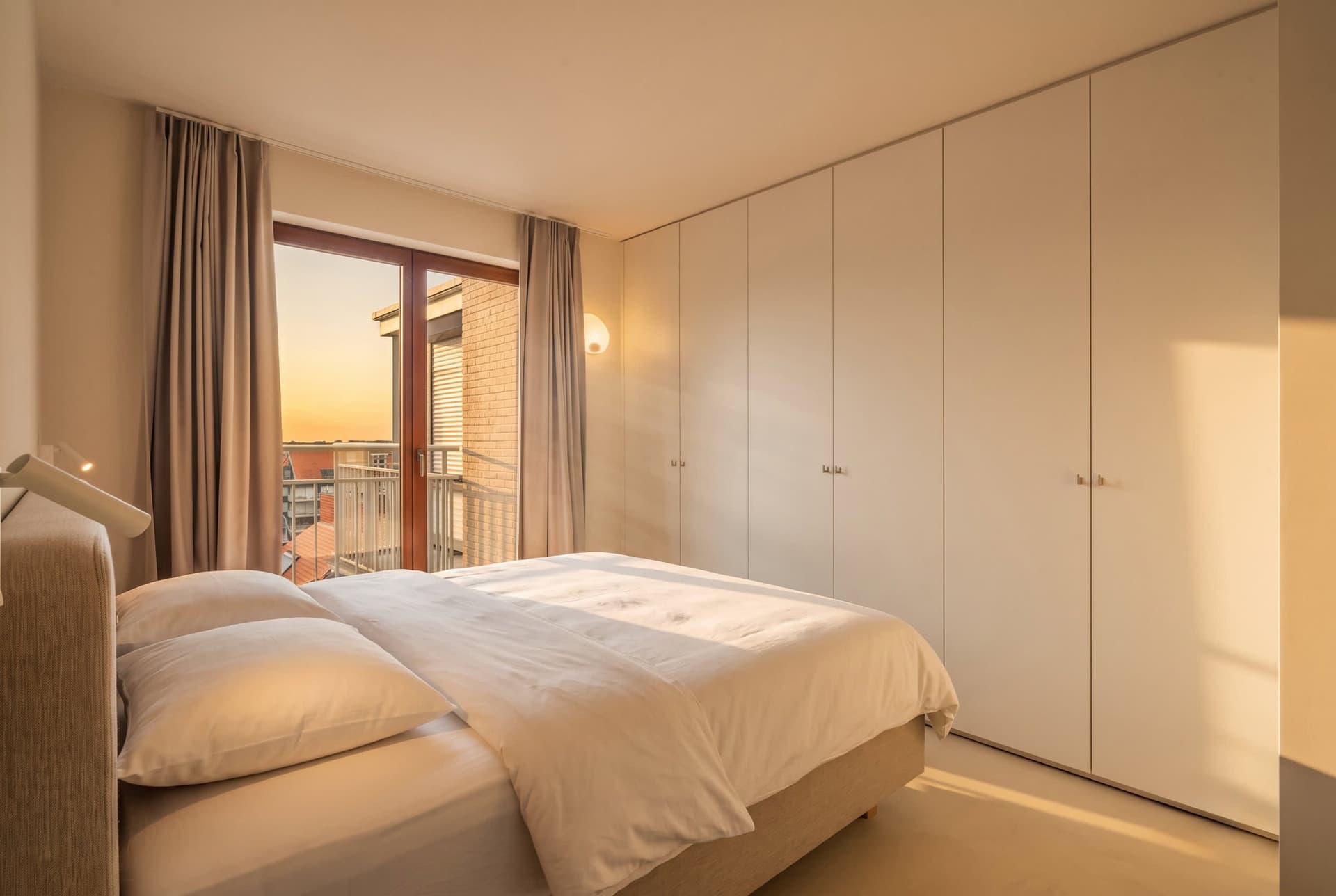 Slaapkamer met dubbel bed, kasten tot aan het plafond en een deur naar het achterbalkon.