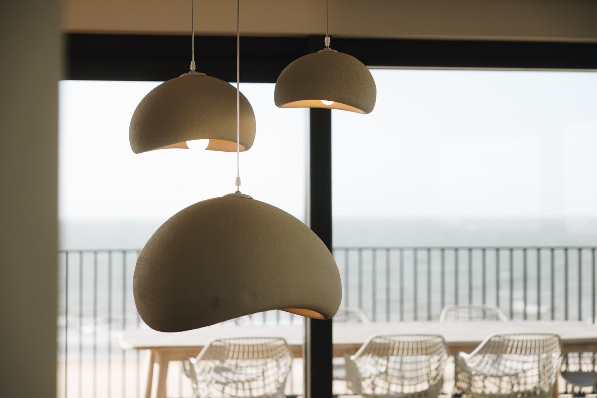 Hanglampen boven de eettafel, zee achter het raam.